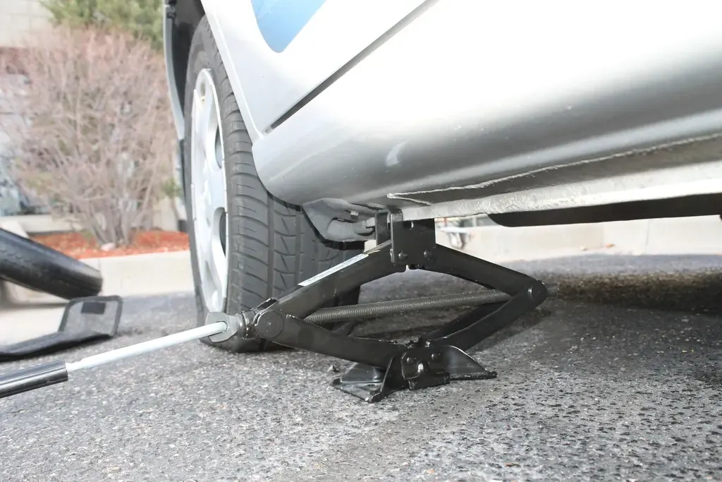Voiture sur cric pendant le changement d'une roue crevée